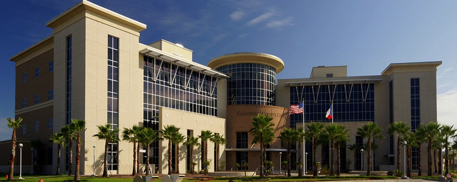 Galveston County Justice Center building with palm trees and flags in Galveston, TX