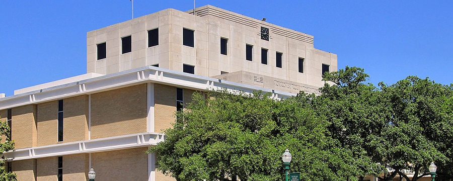 Montgomery County Courthouse building with trees and clear sky in Conroe, TX
