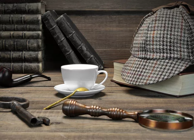 Classic private detective tools with magnifying glass, hat, and books on a wooden desk