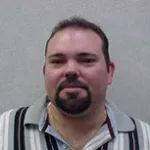 Clay Buckner headshot wearing a striped polo shirt with a neutral background