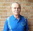Wayne Kessler wearing a blue polo shirt standing against a brick wall